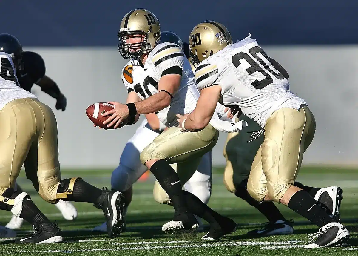 A running back carrying the football through a crowded field