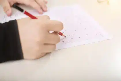 Hands using a tablet at a conference table with blurred whiteboard and documents