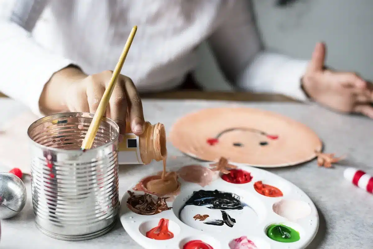 Makeup artist holding a prosthetic hand and applying paint in a workshop