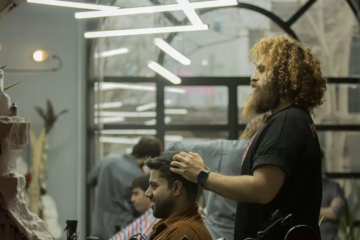 Close-up of a stylist applying K-tip hair extensions to fine hair