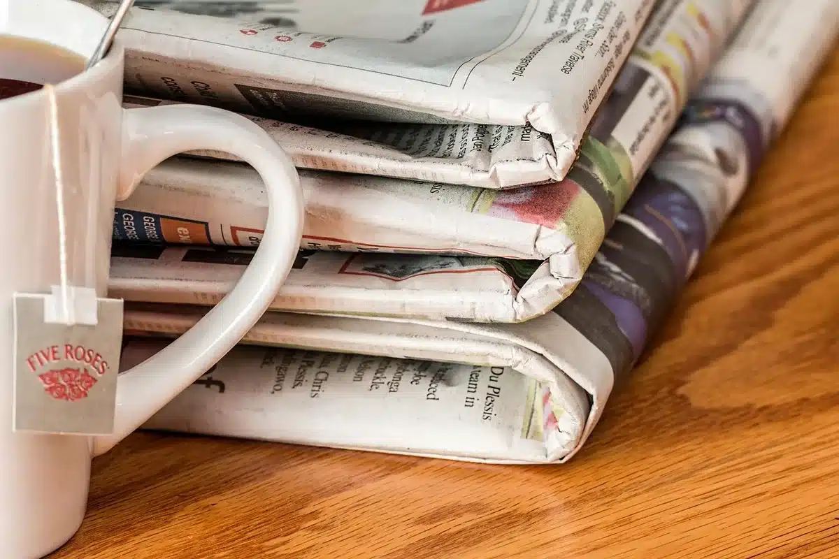 Unbranded newspapers beside a laptop representing training data for AI