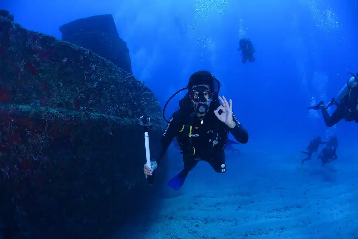 Diver silhouette inspecting a rusted shipwreck covered in marine life