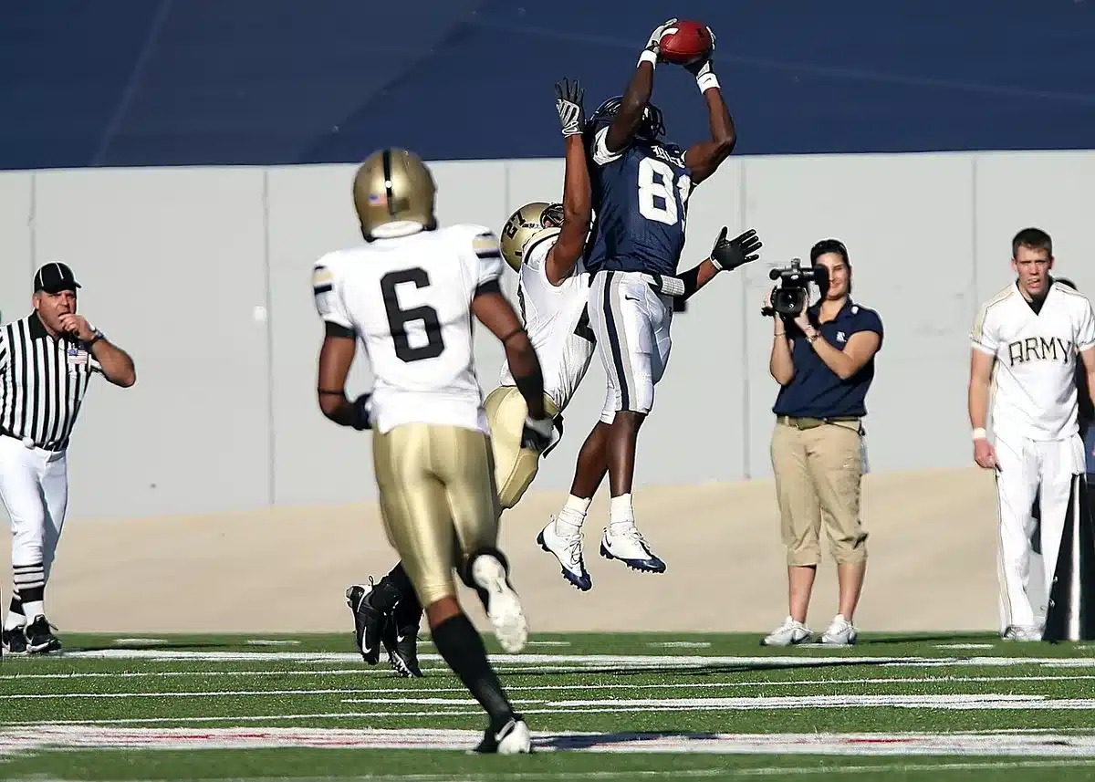Receiver hauling in a contested catch with defenders closing