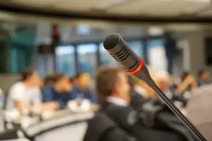Silhouetted executives around a conference table with microphones and folders