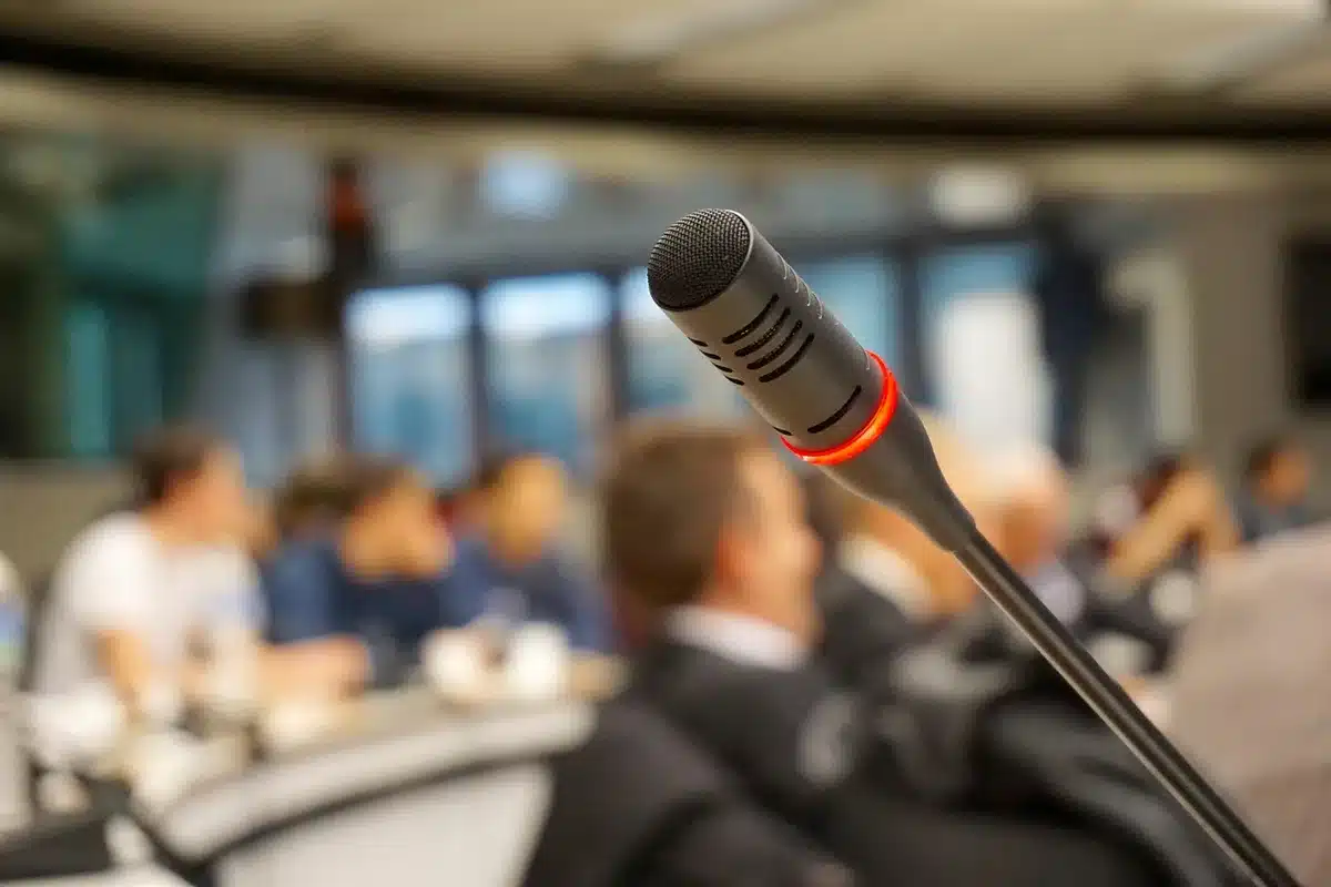 Silhouetted executives around a conference table with microphones and folders