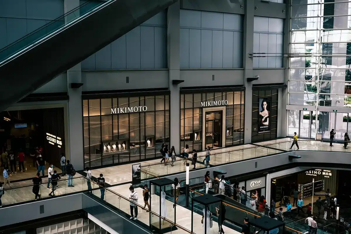 Small crowd at a mall pop-up performance with branded storefronts blurred