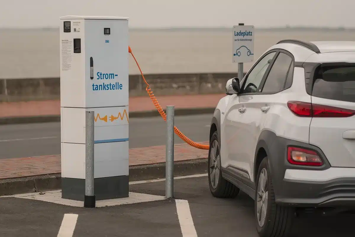 Close view of a hybrid car near a charging cable and a gas pump