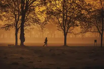 Silhouette of a runner passing vendor tents near a festival stage at sunrise