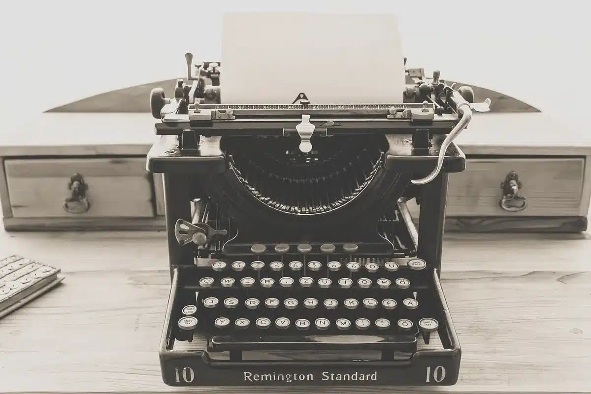 Typewriter and loose manuscript pages on a rooftop at dusk, evoking a writer's solitude
