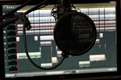 Hands holding microphones over a small podcast mixing console on a table