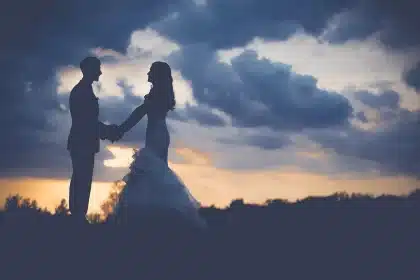 Silhouetted couple walking beside a riverside boardwalk with a tour boat docked
