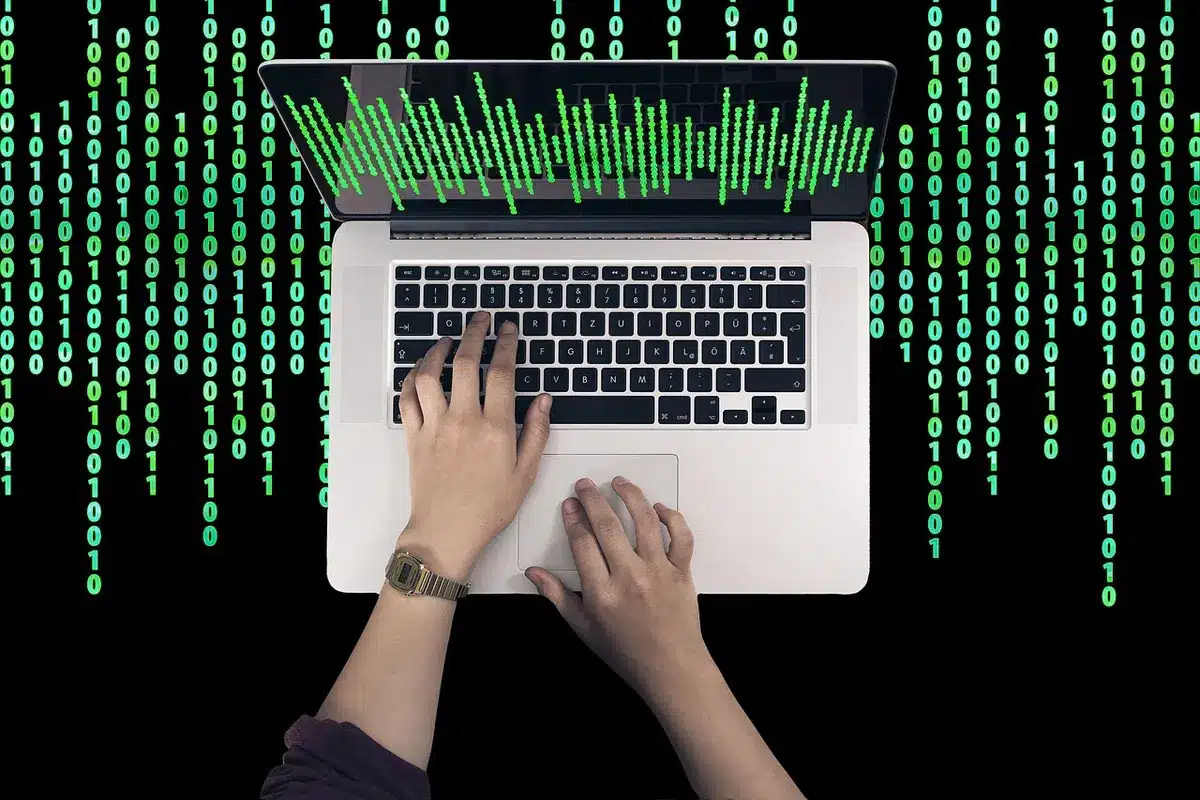 Anonymous laptops and hands around a table with blurred forum posts and code visible on screens