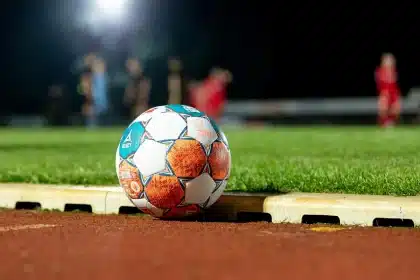 Silhouette of youth soccer boots and ball on a sideline with stadium lights