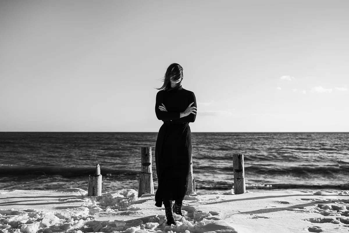 Minimal wardrobe with neutral coats and a pair of boots visible